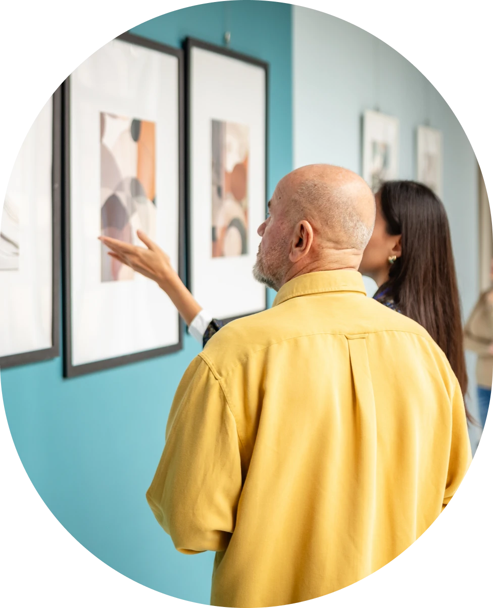 Two individuals admiring framed artwork